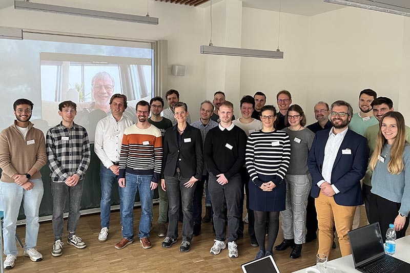 Gruppe von Erwachsenen bei einem Gruppenfoto in einem Seminarraum mit Namensschildern.