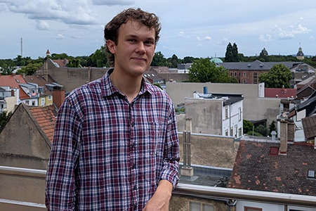 Yannic Flad steht auf einem Balkon vor der Stadtkulisse Karlsruhes.